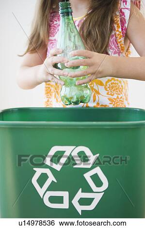 Stock Photograph - Close up of girl (6-7) throwing plastic bottle to recycling bin. Fotosearch