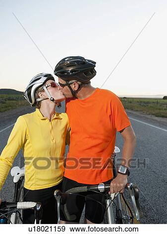 Couple of cyclists kissing on empty road View Large Photo Image Stock Photo - Couple of cyclists kissing on empty road. Fotosearch