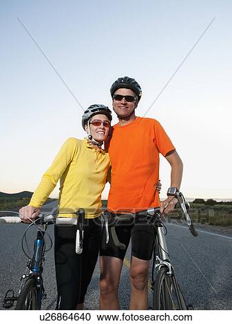 Couple of cyclists posing for portrait on empty road View Large Photo Image Stock Image - Couple of cyclists posing for portrait on empty road. Fotosearch