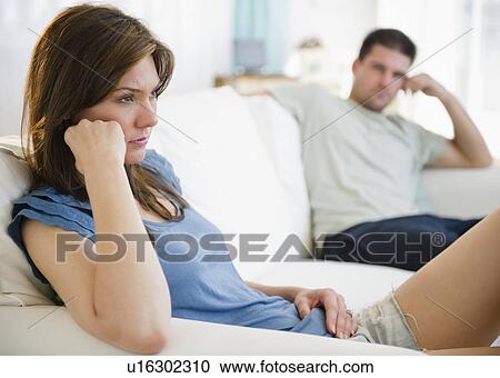 Stock Image - Couple on sofa having relationship problems. Fotosearch