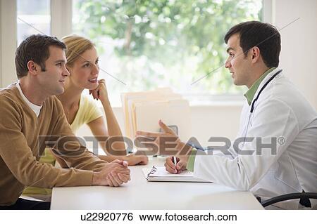 Couple receiving advice from doctor in office View Large Photo Image Stock Photograph - Couple receiving advice from doctor in office. Fotosearch