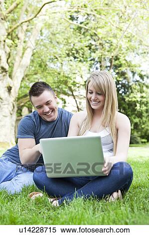 Couple using laptop in park View Large Photo Image Stock Photography - Couple using laptop in park. Fotosearch