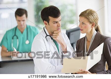 Stock Photograph - Doctor and businesswoman discussing files. Fotosearch