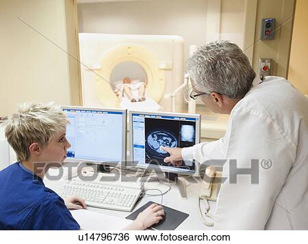 Stock Photograph - Doctor and nurse looking at CAT scan of patient's brain. Fotosearch