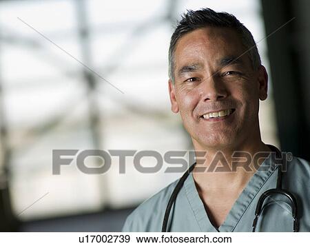 Stock Photo - Doctor in medical scrubs smiling at camera. Fotosearch