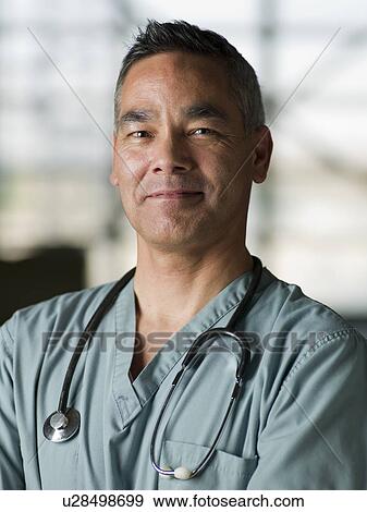 Stock Photo - Doctor in medical scrubs smiling at camera. Fotosearch