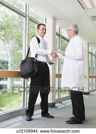 Doctor talking with pharmaceutical representative in hospital corridor View Large Photo Image Picture - Doctor talking with pharmaceutical representative in hospital corridor. Fotosearch
