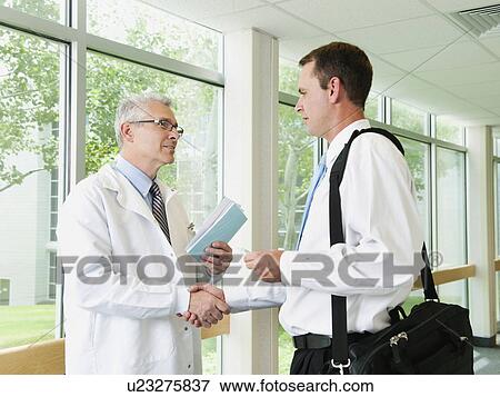 Stock Photo - Doctor talking with pharmaceutical representative in hospital corridor. Fotosearch
