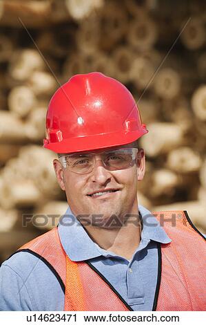 Stock Image - Engineer in front of stack of timber. Fotosearch