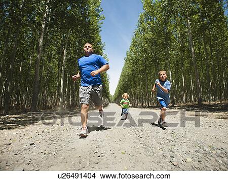 Father with sons (2-9) running down country road View Large Photo Image Picture - Father with sons (2-9) running down country road. Fotosearch
