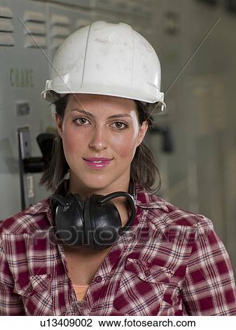 Female in hard hat and ear protectors in industrial setting View Large Photo Image Stock Image - Female in hard hat and ear protectors in industrial setting. Fotosearch