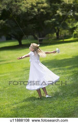 Stock Photo - Flower girl (10-11) dancing on grass. Fotosearch