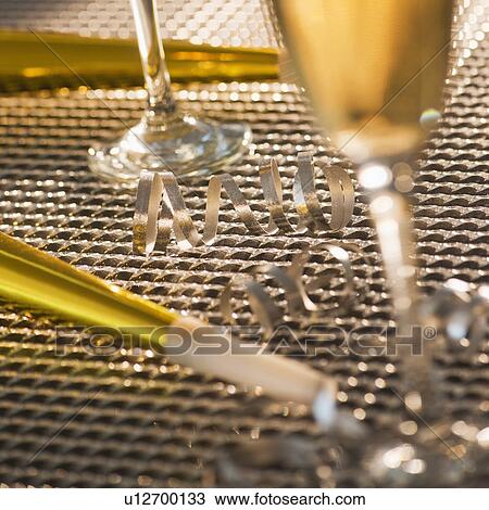 Stock Image - Flutes with champagne and party horn blowers. Fotosearch