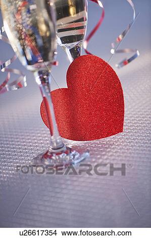 Flutes with champagne and red paper heart, close-up View Large Photo Image Picture - Flutes with champagne and red paper heart, close-up. Fotosearch