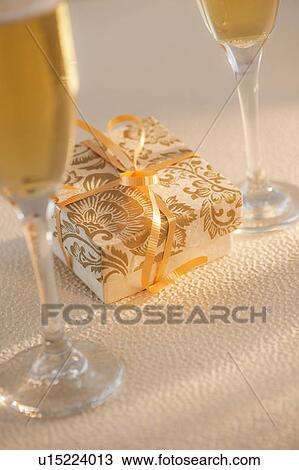 Flutes with champagne and small gift box View Large Photo Image Stock Image - Flutes with champagne and small gift box. Fotosearch