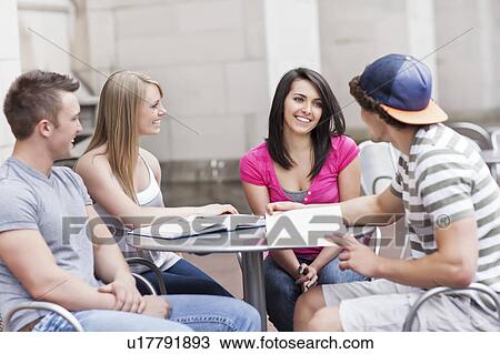 Four college students sitting at cafe table View Large Photo Image Stock Image - Four college students sitting at cafe table. Fotosearch