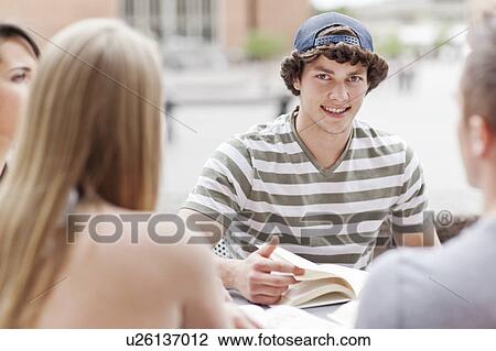 Four college students sitting at cafe table View Large Photo Image Stock Image - Four college students sitting at cafe table. Fotosearch