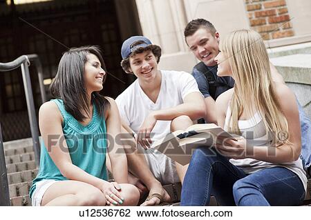 Stock Image - Four college students sitting on steps. Fotosearch