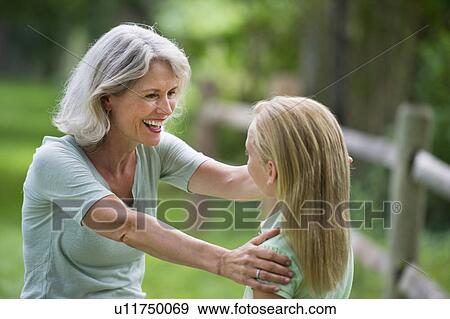 Stock Photo - Girl (10-11) and grandmother laughing togetherness. Fotosearch