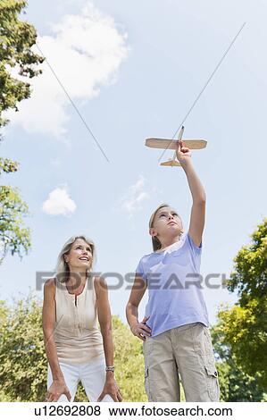 Stock Photo - Girl (10-11) and grandmother playing with toy plane. Fotosearch