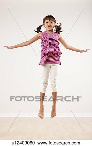 Stock Image - Girl (10-11) jumping, studio shot. Fotosearch