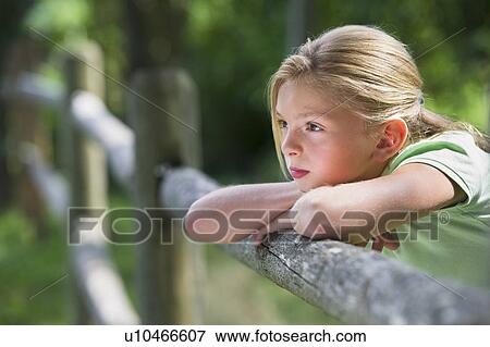 Girl (10-11) leaning on fence View Large Photo Image Stock Photo - Girl (10-11) leaning on fence. Fotosearch