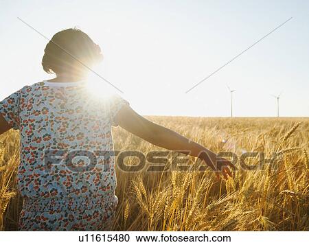 Girl (10-11) walking in glorious sunshine amidst wheat View Large Photo Image Stock Image - Girl (10-11) walking in glorious sunshine amidst wheat. Fotosearch