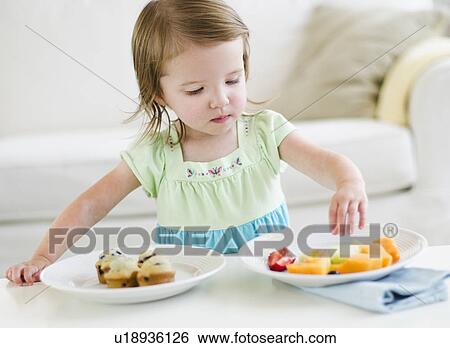 Girl (2-3) choosing between fruit salad and muffins View Large Photo Image Stock Photograph - Girl (2-3) choosing between fruit salad and muffins. Fotosearch