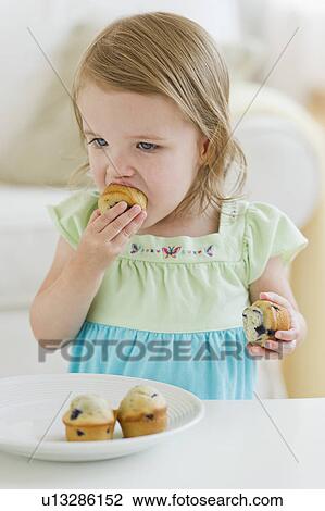 Stock Image - Girl (2-3) eating muffins. Fotosearch