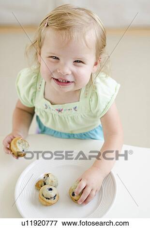 Stock Photo - Girl (2-3) eating muffins. Fotosearch