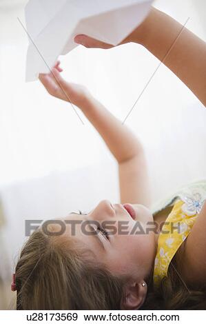 Stock Photo - Girl ( 6-7) playing with paper plane. Fotosearch