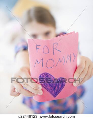 Stock Image - Girl ( 6-7) showing greeting card for mother's day. Fotosearch
