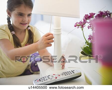 Stock Image - Girl ( 6-7) turning off lamp. Fotosearch