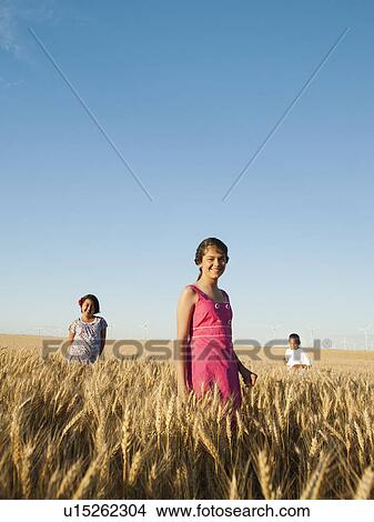 Girls (10-11, 12-13) and boy (8-9) standing in wheat field View Large Photo Image Picture - Girls (10-11, 12-13) and boy (8-9) standing in wheat field. Fotosearch