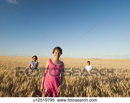 Stock Photography - Girls (10-11, 12-13) and boy (8-9) standing in wheat field. Fotosearch