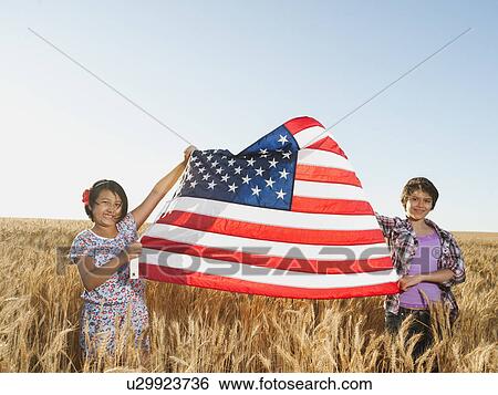 Girls (10-11, 12-13) holding american flag in wheat field View Large Photo Image Stock Photograph - Girls (10-11, 12-13) holding american flag in wheat field. Fotosearch