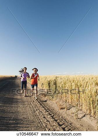 Girls (12-13, 10-11) running along dirt road View Large Photo Image Stock Photo - Girls (12-13, 10-11) running along dirt road. Fotosearch