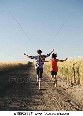Girls (12-13, 10-11) running along dirt road View Large Photo Image Stock Photo - Girls (12-13, 10-11) running along dirt road. Fotosearch