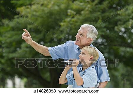 Stock Photo - Grandfather and grandson (10-11) in park. Fotosearch