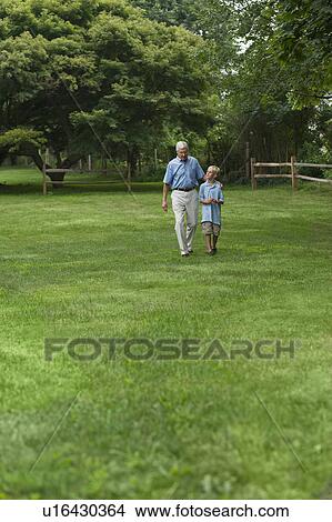 Picture - Grandfather and grandson (10-11) walking in park. Fotosearch