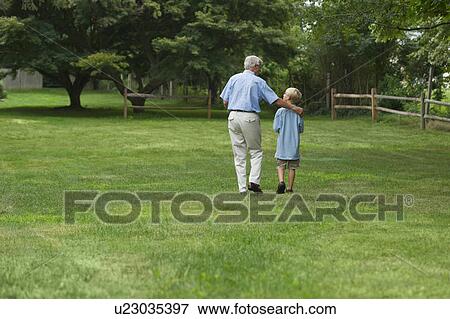 Stock Photo - Grandfather and grandson (10-11) walking in park. Fotosearch
