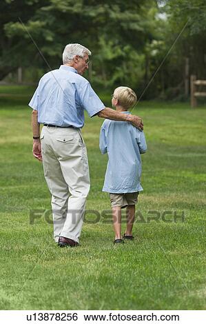 Stock Photograph - Grandfather and grandson (10-11) walking in park. Fotosearch