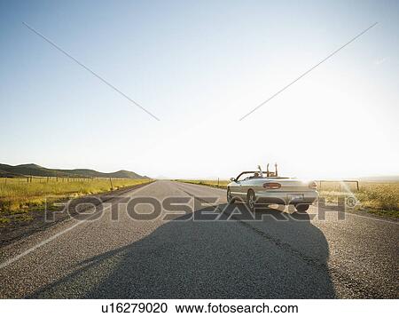Stock Image - Happy couple driving on empty road. Fotosearch
