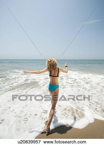 Happy young woman running in to sea View Large Photo Image Stock Photo - Happy young woman running in to sea. Fotosearch