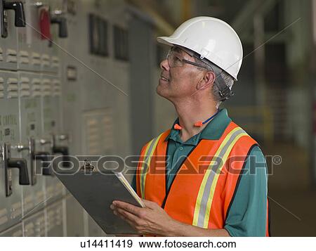 Stock Photo - Industrial worker in hard hat writing on clipboard. Fotosearch