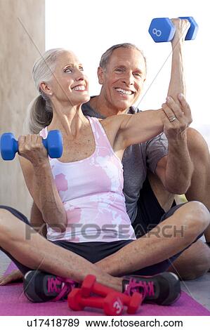 Man assisting woman lifting dumbbells View Large Photo Image Stock Photo - Man assisting woman lifting dumbbells. Fotosearch