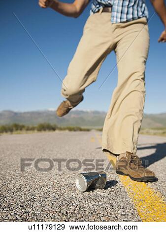 Stock Photo - Man kicking tin can on otherwise empty road. Fotosearch