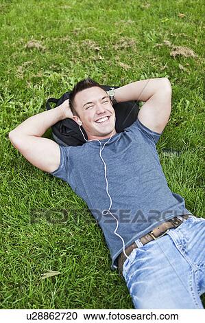 Man lying on grass listening to mp3 player View Large Photo Image Stock Image - Man lying on grass listening to mp3 player. Fotosearch