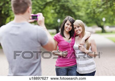 Man taking picture of two women in park View Large Photo Image Stock Photo - Man taking picture of two women in park. Fotosearch