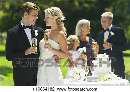 Married couple holding champagne flute, guests in background View Large Photo Image Stock Image - Married couple holding champagne flute, guests in background. Fotosearch